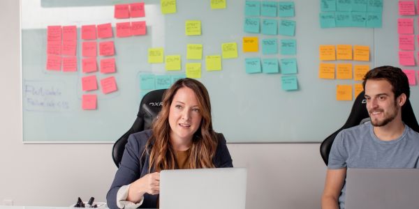 700x350 two people sitting at table with post it notes stuck behind them wo people sitting at table with post it notes stuck behind them