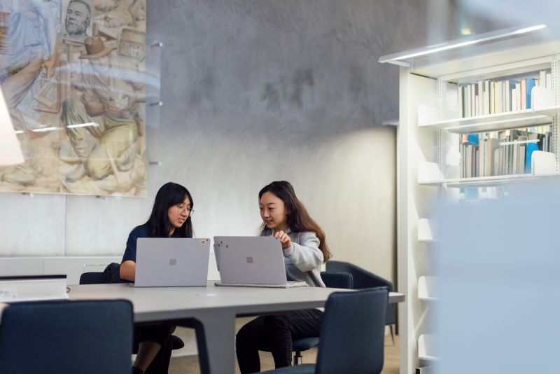 two students sitting together in a discussion on their laptops