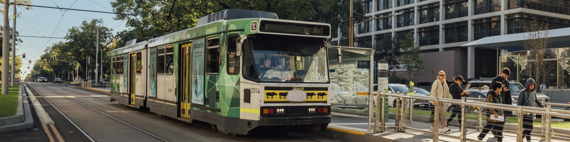 Passengers disembarking from a green and white Melbourne tram
