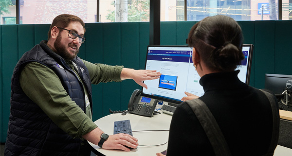 A person at a computer assisting someone with an enquiry