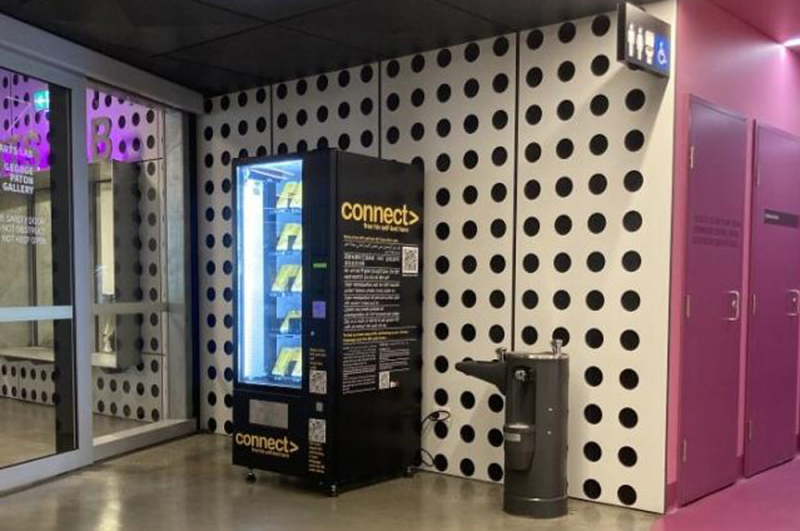 A vending machine in a colourful, brightly lit hallway.