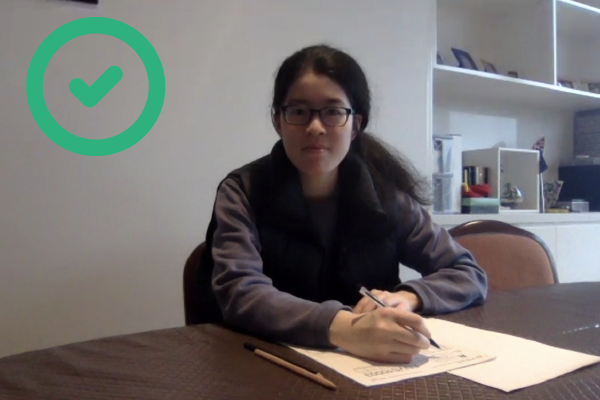 Student sitting an online exam. Acceptable - this student is using a printed exam, and their face is clear and visible for identificaton.