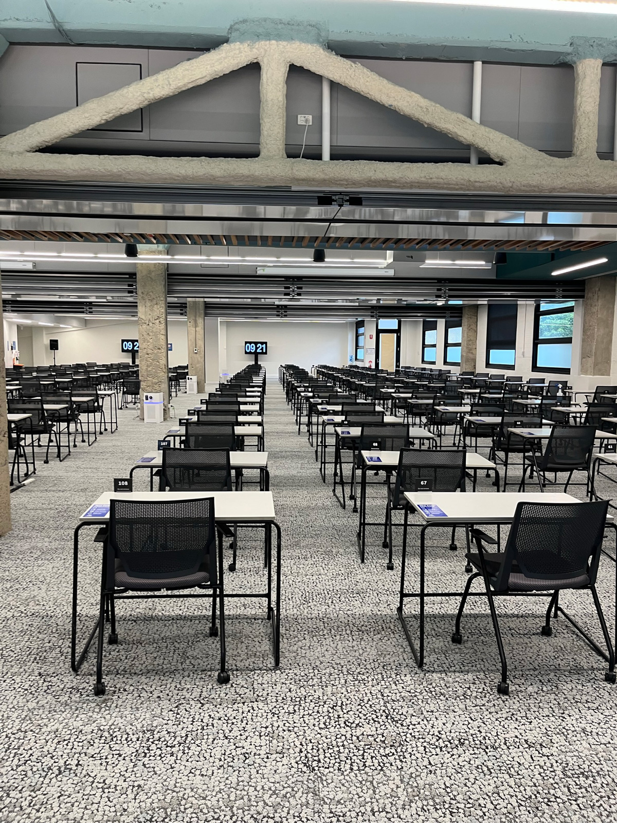 Many rows of individual chairs and desks for exams.