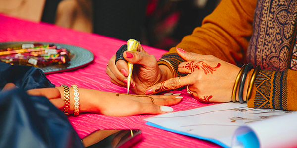 Person getting hands decorated with henna tattoos