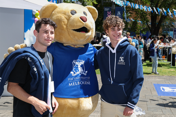 Two students standing with Barry the Bear mascot