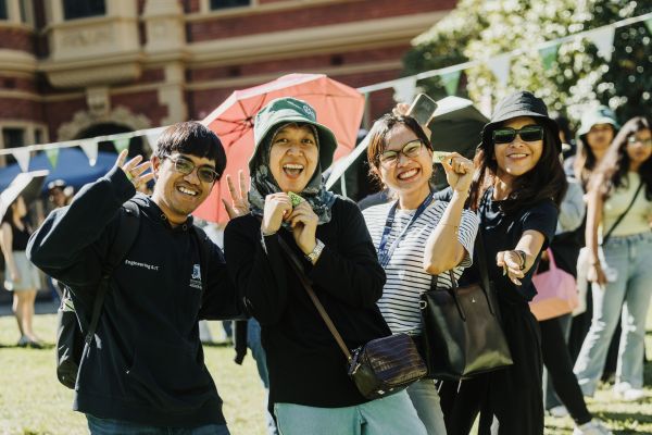 Four students smiling in front of GSA building