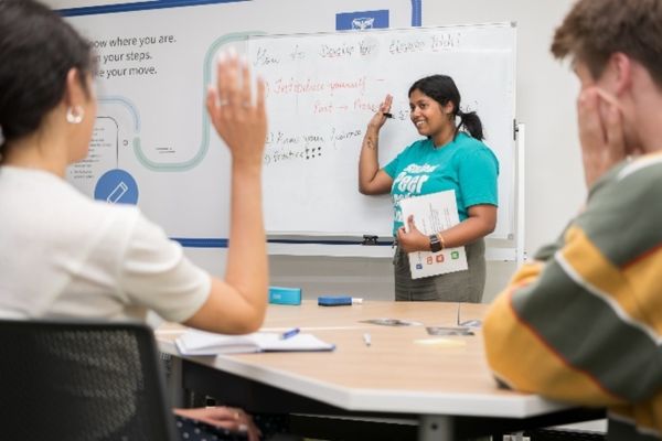 A Student Peer Leader Network member stands at a whiteboard delivering a presentation on how to develop an elevator pitch