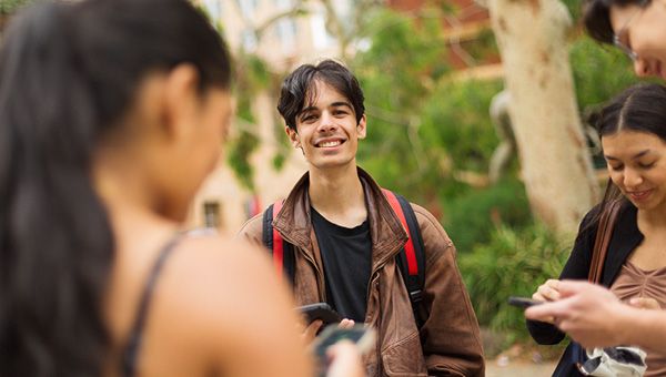A group of student are talking in an outdoor area of campus between classes.