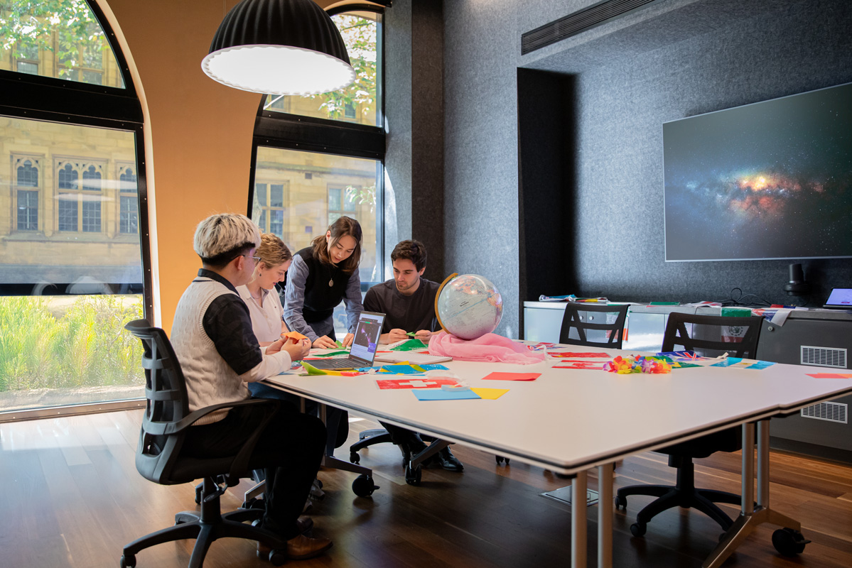 Four people work together at a table with a globe.