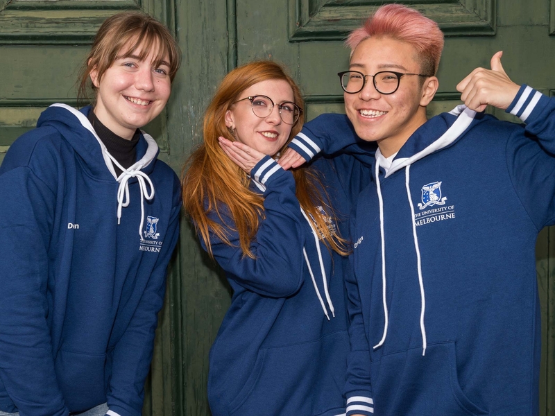 Three students standing together in University of Melbourne hoodies