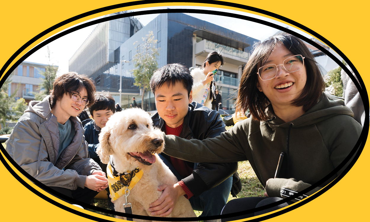 Three students sitting happily with a dog