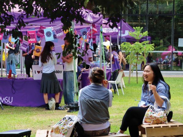 students on the lawn in front of UMSU purple marquees