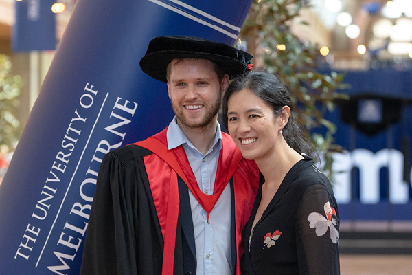 Two people posing; one in academic regalia.