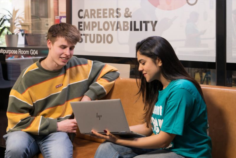 Two students looking at a laptop inside a Careers and Employability Studio.