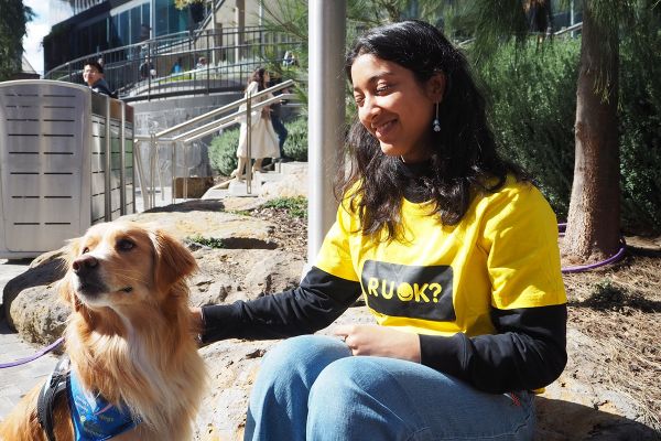 R U OK Day 2026 Person wearing an R U OK Day t-shirt smiling in the sunshine with a therapy dog