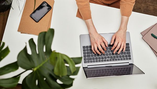 A student works on a laptop while seated at a desk.