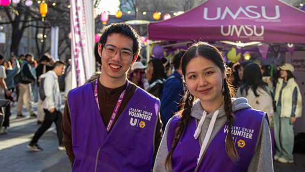 Two Student Union representatives speak with new students at an outdoor orientation event.