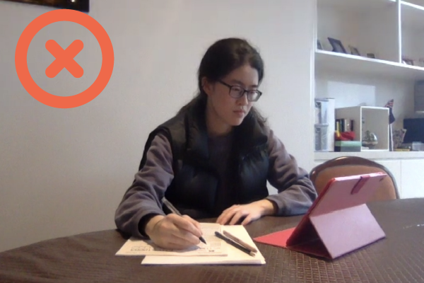 Student sitting an online exam. Unacceptable - the device being used to read the exam paper is not visible.