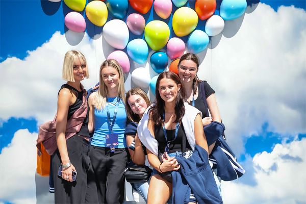 Group of young women with balloons and clouds backdrop