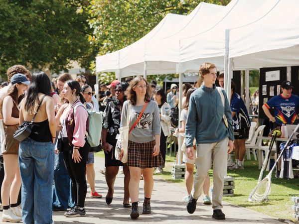 Students walking on campus and looking at white marquees