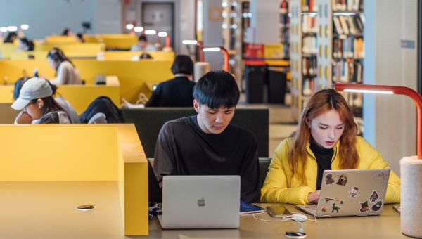 A group of students are working from study spaces within a University of Melbourne library.