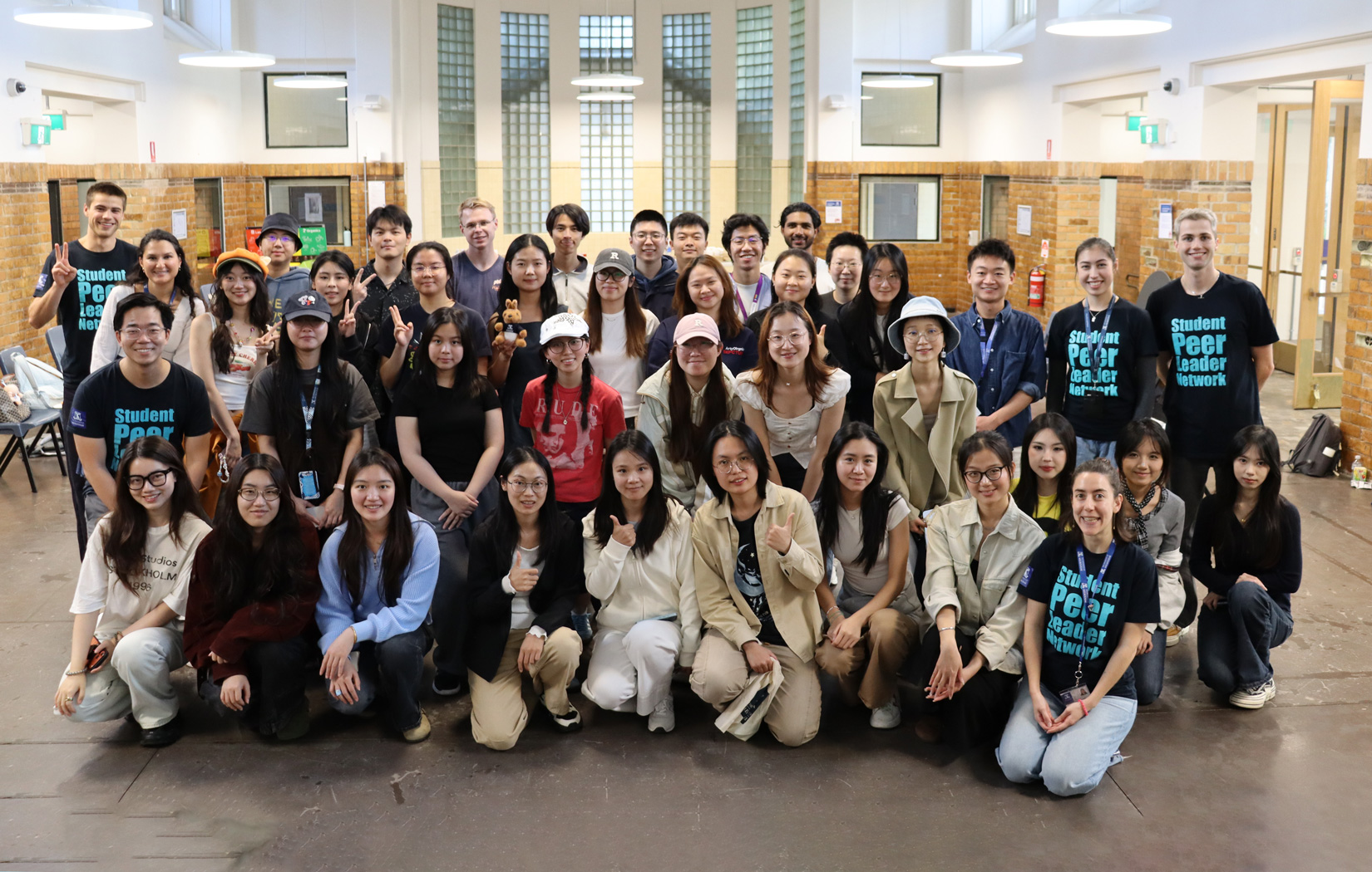 A crowd of students poses for a group photo inside a large hall.