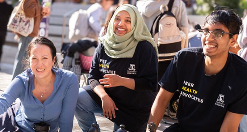 Three smiling students—including two wearing 