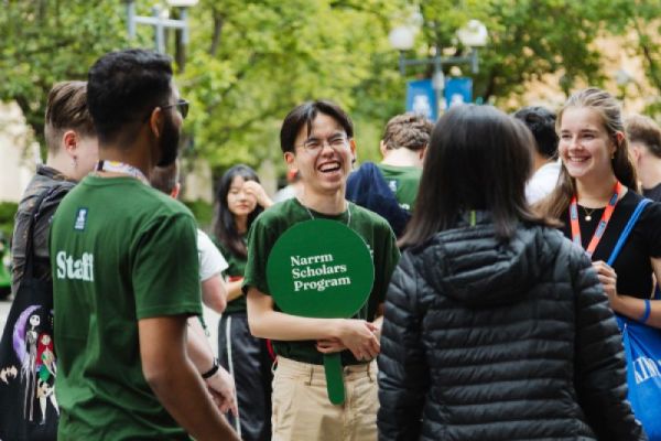 Two Narrm Scholars representatives speak with new students at an outdoor orientation event.
