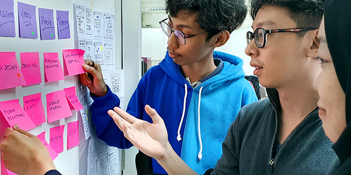 Three students using fluro PostIt notes