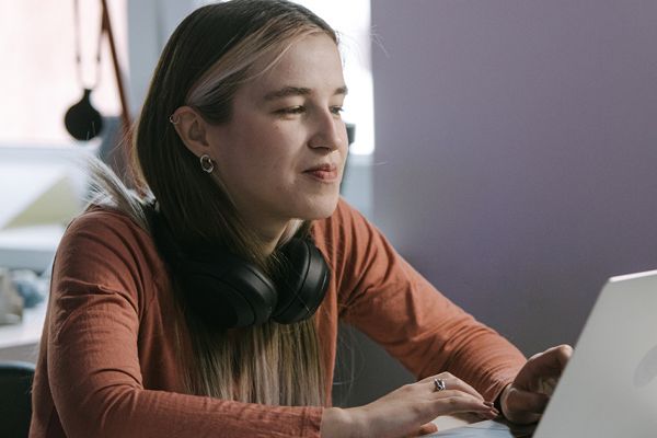 Image of person sitting at laptop with headphones around their neck.