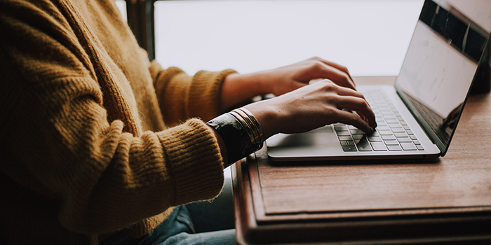 EmpWk2023_EventTiles_700x350px_MASTER_FILE_LAPTOP Person in mustard jumper writing on laptop