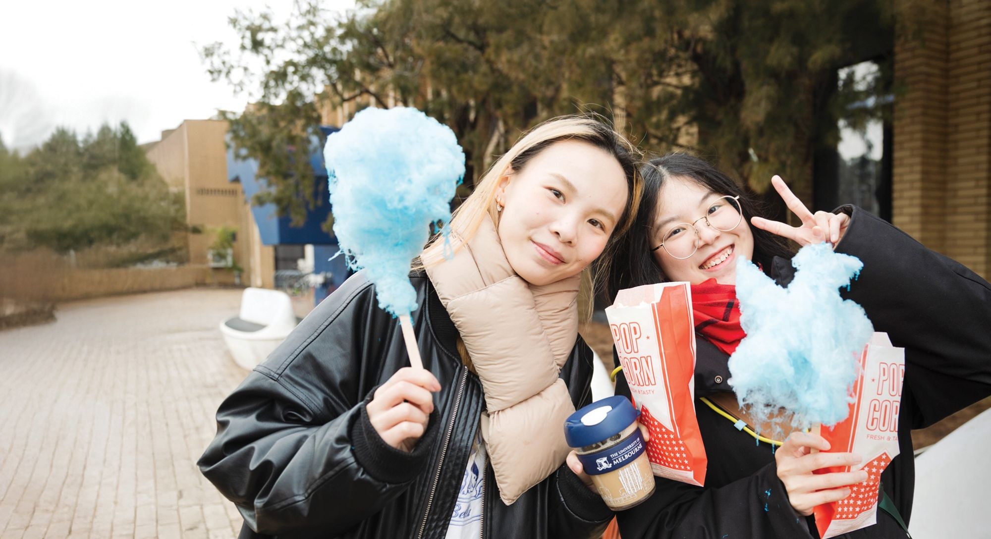 Two students holding popcorn and fairy floss
