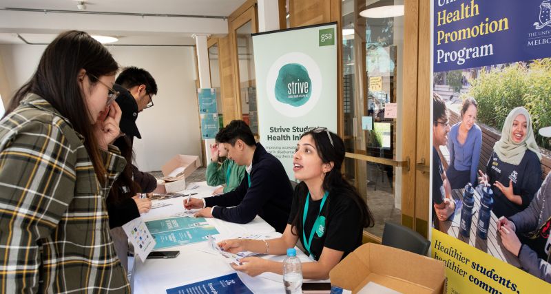 An group of students and staff interact at health-focused information stalls.
