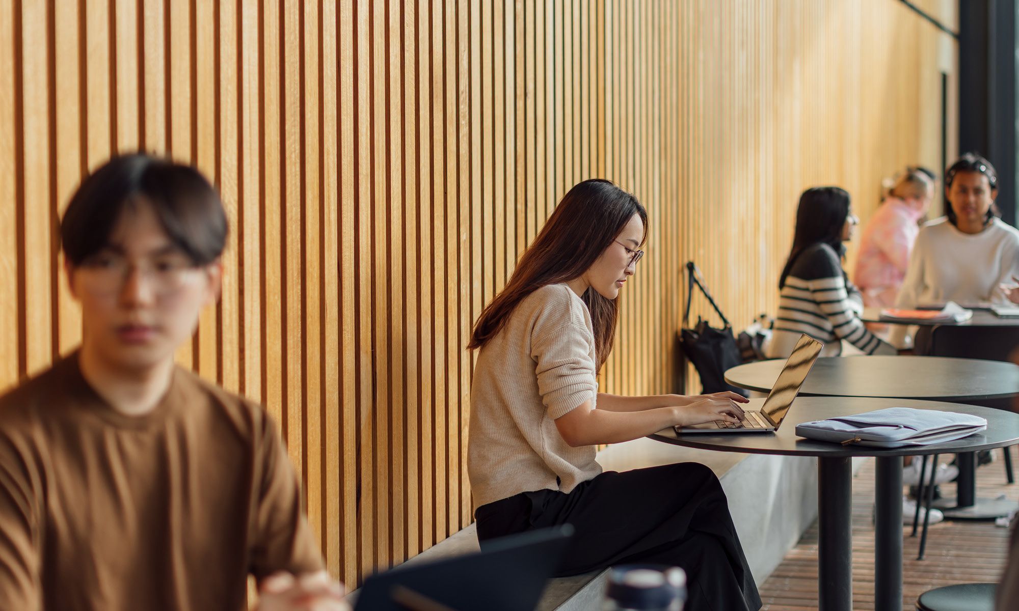 A student works on a laptop in a shared study space.