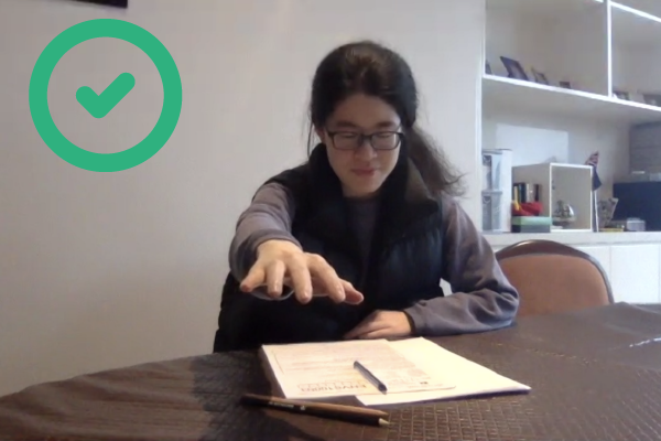 Student sitting an online exam. Acceptable - this student has ensured that their hand is not out of view if they reach forward.